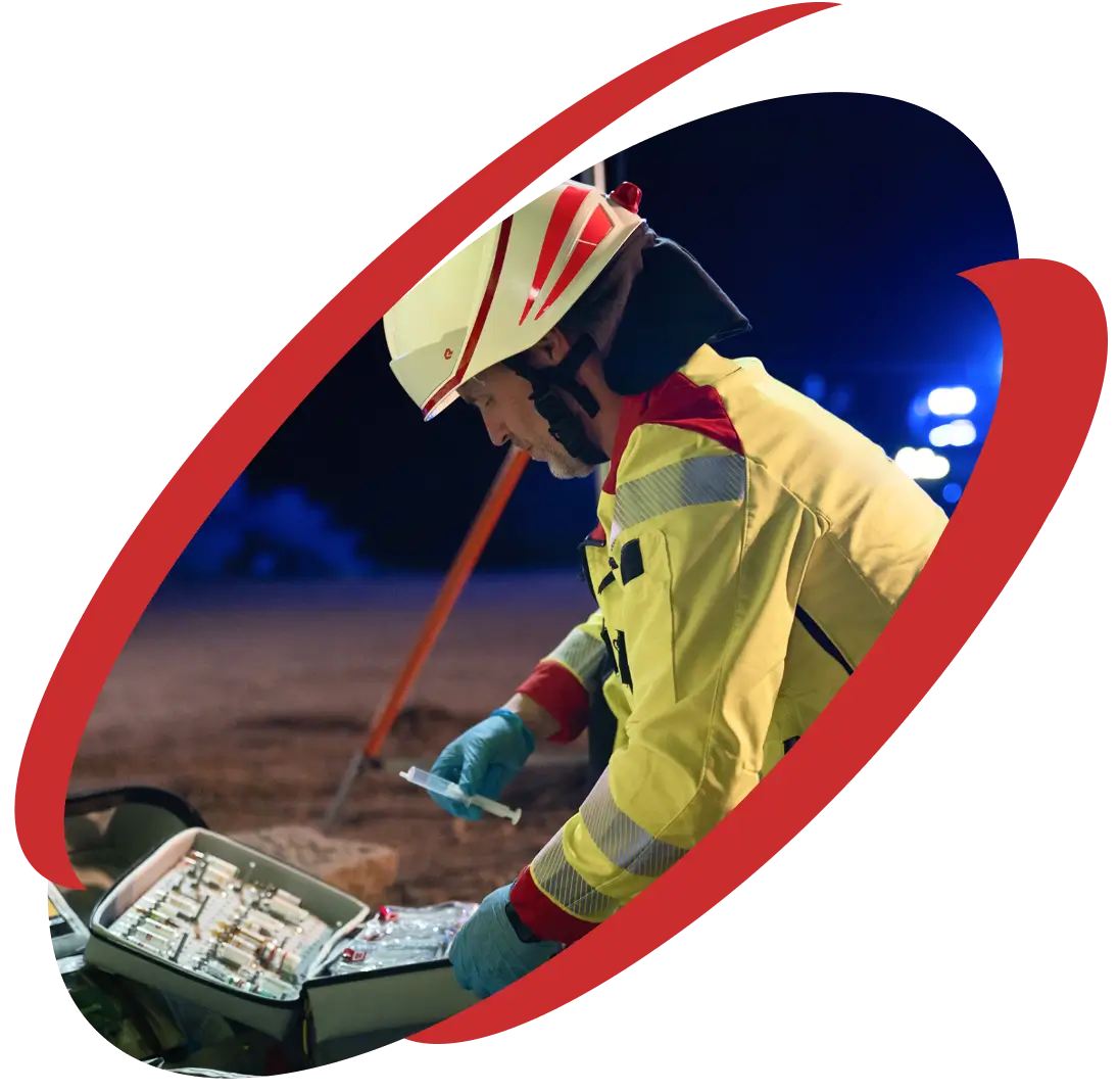 Sanitäter in Schutzkleidung bereitet medizinische Ausrüstung bei einem nächtlichen Einsatz auf der Baustelle vor.