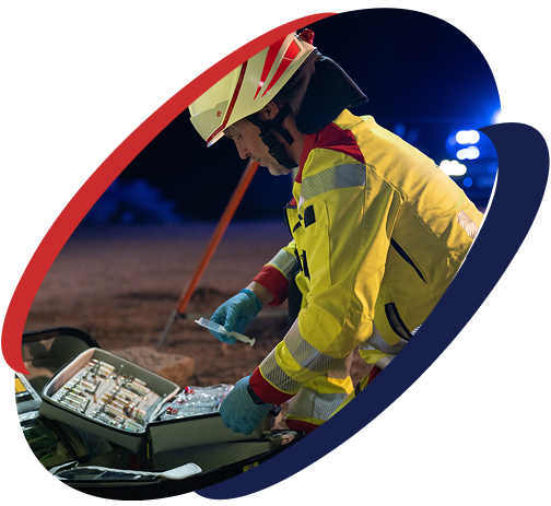 Sanitäter in Schutzkleidung öffnet medizinische Ausrüstung bei einem nächtlichen Einsatz.