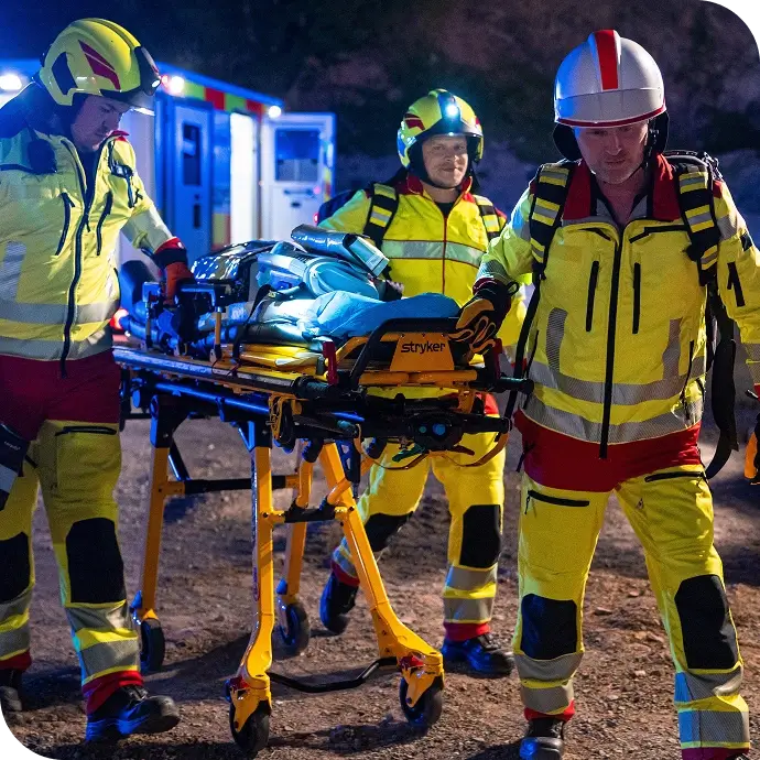 Drei Sanitäter transportieren nachts eine verletzte Person auf einer Trage zu einem Rettungswagen.