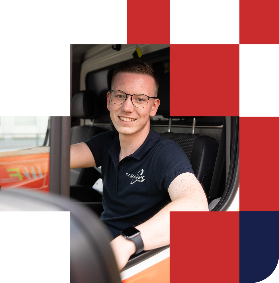 Junger Sanitäter sitzt im Einsatzfahrzeug von ParaQare und lächelt in die Kamera.