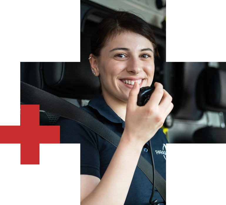 Lächelnde Sanitäterin im Einsatzfahrzeug spricht über Funkgerät während eines Einsatzes.